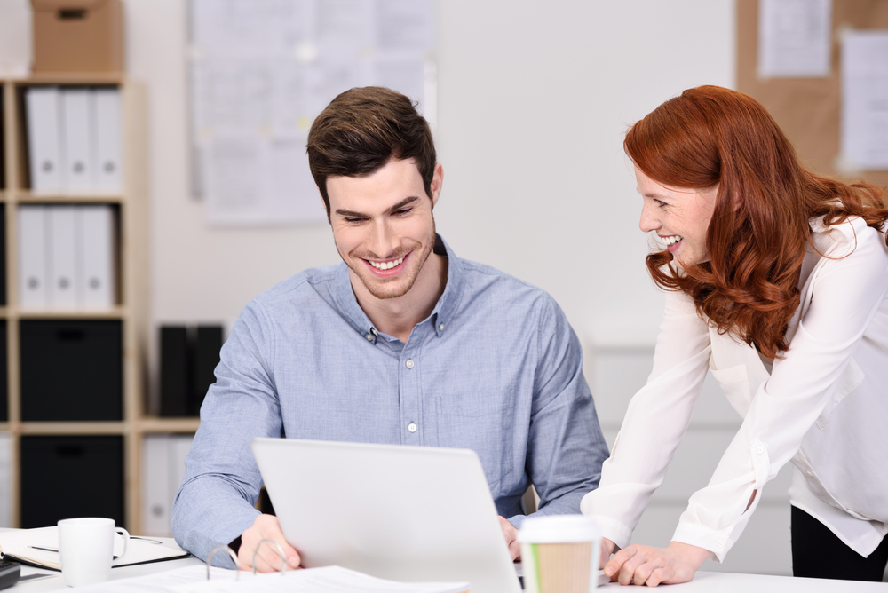 A man and a woman look at laptop while discussing ERP platform